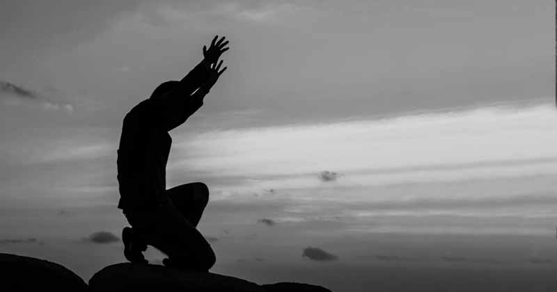 silhouette of man with hands lifted high