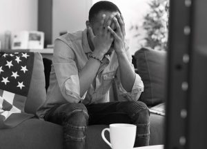 man sitting on sofa dealing with feelings of shame and gulit