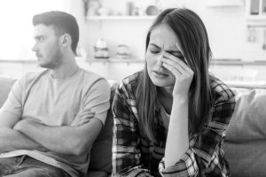 crying angry woman sits on couch next to annoyed man, steps to marriage restoration