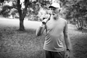 senior man walking outdoors with a water bottle in hand. Sharing faith through healthy living concept