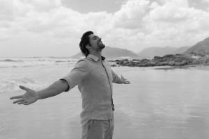 man standing on beach with arms open, experiencing spiritual freedom concept